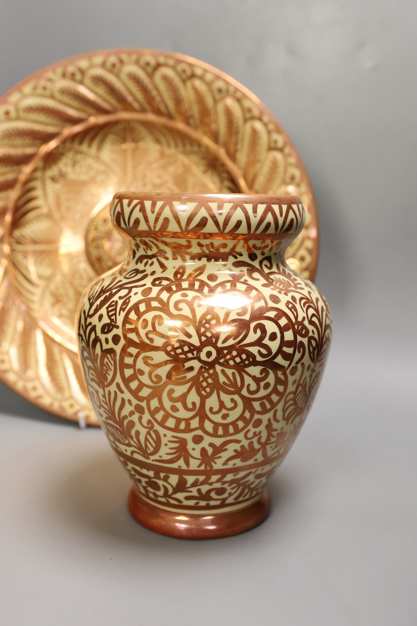 A Hispano Moresque style copper lustre pottery charger and vase, 24cm tall